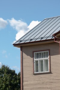 side of a tan house with a metal roof